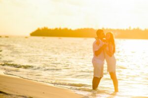 Newlyweds on their honeymoon standing on the beach during sunset